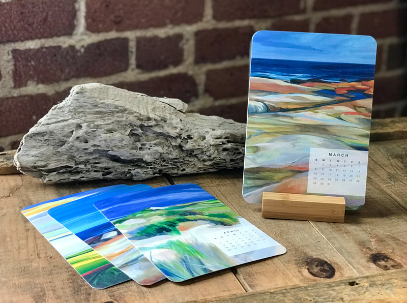 A small wooden block holds 5x7" cards with cropped images of Deidre Tao's artwork on them, including a small block of text showing the month and days of each month of the year, one month per card. There are twelve cards in the packet.