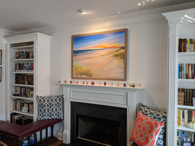 A large painting of a New England beach painted by Deidre Tao graces a mantelpiece setting in a classic home decor.